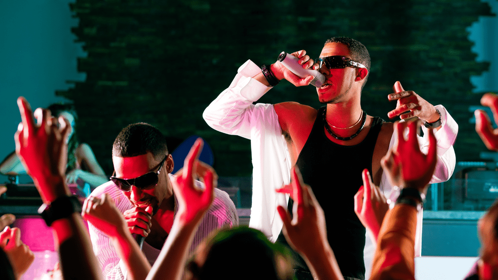 A man dressed in a white shirt and sunglasses gestures with his hands, capturing the dynamic spirit of the hip-hop culture.